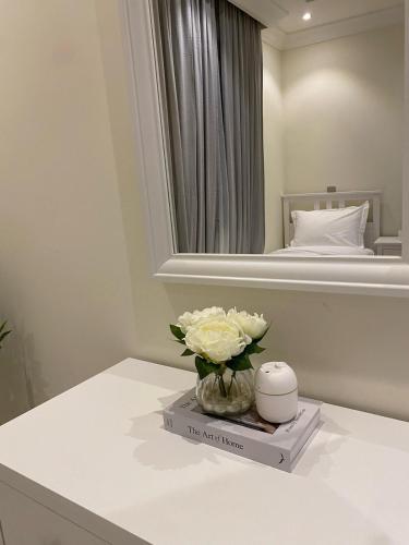 a table with a vase of flowers on a book at شقة بغرفتي نوم وغرفة معيشة in Jeddah