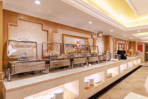 a restaurant with a buffet line with plates and bowls at Vienna International Hotel in Xiamen