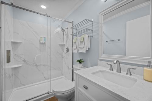 a white bathroom with a toilet and a shower at Pet-Friendly 3 BR Home with King Bed and Fenced Yard Near Downtown in New Bern