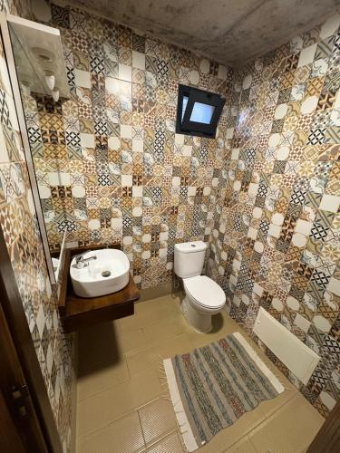 a bathroom with a toilet and a tv on the wall at Victoria Ocean View Room in Ponta do Pargo