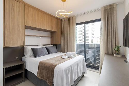 a bedroom with a large bed and a large window at Log! | Rooftop com vista, coworking, garagem e localização imbatível | Gonzaga Stays in Curitiba