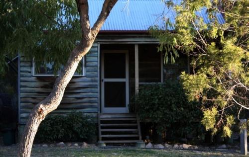 a wooden house with a porch and stairs to the door at Cypress Ridge Cottages in Ballandean