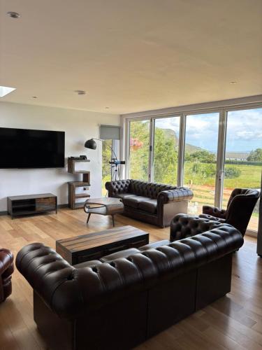 a living room with leather couches and a television at Luxurious, Unique & Elegant Cottage with Hot Tub in Ollach