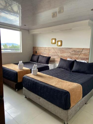 a bedroom with two beds and a large window at Hotel Funza Real in Funza