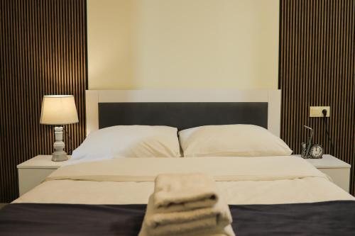 une chambre avec un lit avec des draps blancs et une lampe dans l'établissement Batumi Modern Deluxe Apartment, à Kakhaberi