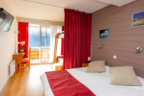 1 dormitorio con 1 cama con cortinas rojas y ventana en Village Vacances Le Tarbesou - Pied de piste station Ax 3 Domaines, en Ax-les-Thermes