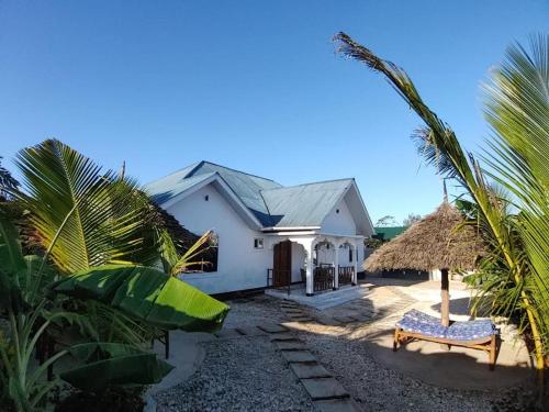 a white house with a straw roof at Malaika White House Apartment & Spa in Kiwengwa