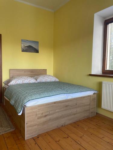 a bedroom with a bed in a yellow wall at Apartmány Obora v Podbezdězí in Doksy