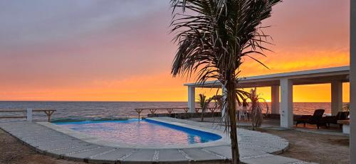 a swimming pool on the beach at sunset at Camahuiroa Bungalows in Camahuiroa