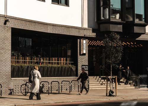 a couple of people walking on a sidewalk in front of a building at One Hundred Shoreditch in London