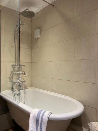 a white bath tub in a bathroom with a shower at Miners Cottage in Bakewell