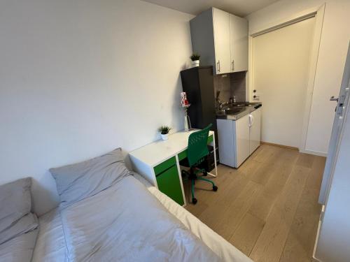Un dormitorio con una cama y un escritorio y una cocina. en Lillestrøm home hybel uten soverom, en Lillestrøm