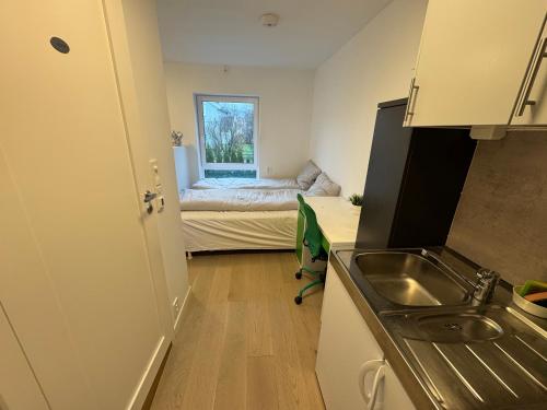 una pequeña cocina con fregadero y un dormitorio en Lillestrøm home hybel uten soverom, en Lillestrøm