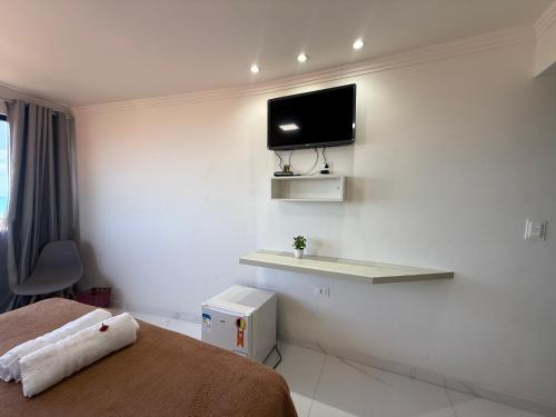 a hotel room with a bed and a tv on the wall at Pousada Maresia in Maragogi