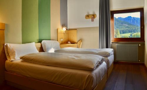 een hotelkamer met twee bedden en een raam bij Hotel Garni Edy in Daiano