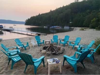 a group of chairs sitting on a beach at Front LAKE Simon HOT TUB 6br 17p BEACH private in Lac-Simon