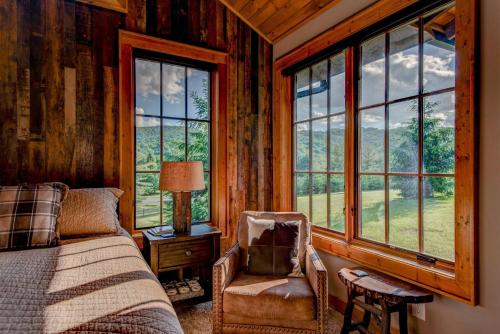 a bedroom with a bed and a chair and windows at Banner View in Banner Elk
