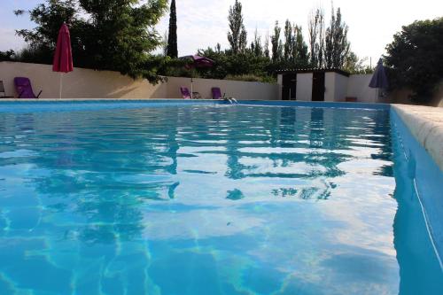 a blue swimming pool with chairs and umbrellas at Hotel Carina in Apt