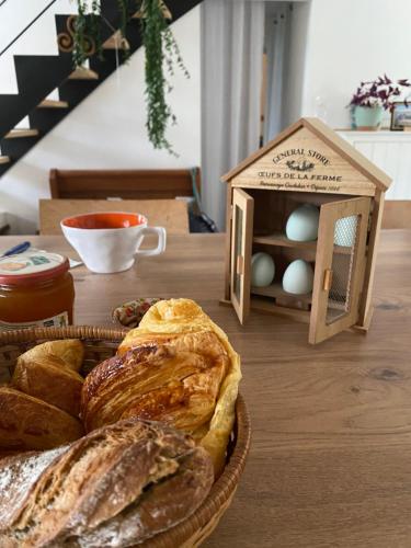 Montauban-de-BretagneにあるChambre privé à deux pas de la gareのパンの入ったバスケットと鳥小屋が置かれたテーブル