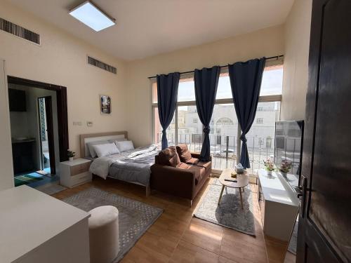 a bedroom with a bed and a couch and a window at استديو لك بالكامل in Abu Dhabi