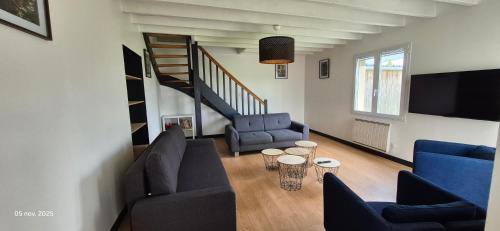 un salon avec deux chaises bleues et une télévision dans l'établissement Gites Le Saint Martin Le Convivial 6-8 people, à Blaslay