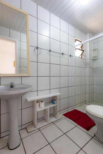 a bathroom with a sink and a toilet and a mirror at Apartamento com Varanda, Churrasqueira e Vista Mar in Meia Praia