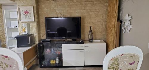 ein Wohnzimmer mit Fernseher und Tisch und Stühlen in der Unterkunft Gite Romantique de Type Charentais in Le Thou