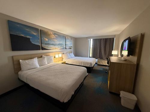 Days Inn by Wyndham Amarillo East في أماريلو: غرفة فندق بها سريران وتلفزيون بشاشة مسطحة