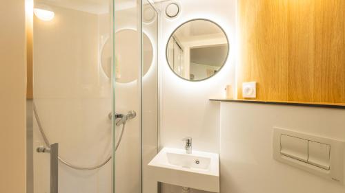 a bathroom with a shower and a sink and a mirror at Premiere Classe Versailles - Saint Cyr L'ecole in Saint-Cyr-lʼÉcole
