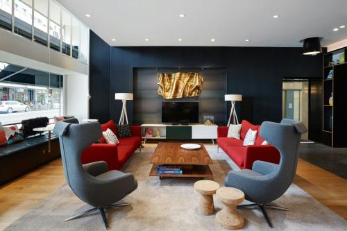 a living room with a red couch and two chairs at citizenM Zürich in Zürich