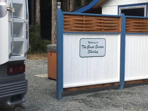 a white shed with a sign that readsjust guest houseshaw at The Great Escape - Shirley & Bunkhouse in Sooke