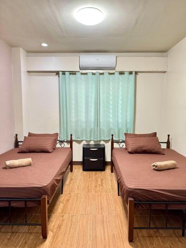 two beds sitting in a room with a window at C7 Plaza and Residences in Iloilo City