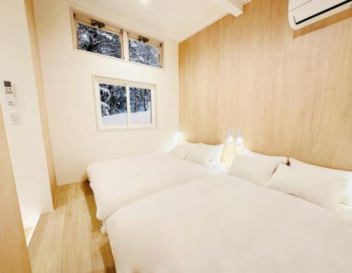 two white beds in a room with two windows at Lagom Hakuba in Hakuba