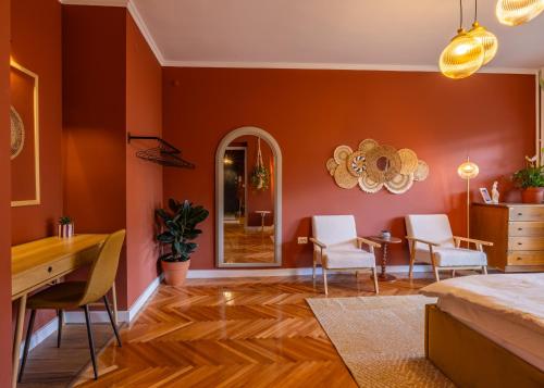 salon z pomarańczowymi ścianami, stołem i krzesłami w obiekcie Square One APT w Prisztinie