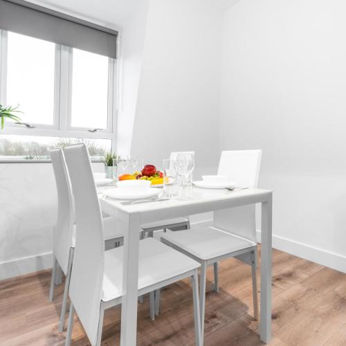a white dining room with a white table and chairs at Modern Two Bed Apartment - Balcony & Parking - Netflix 8MC in Birmingham