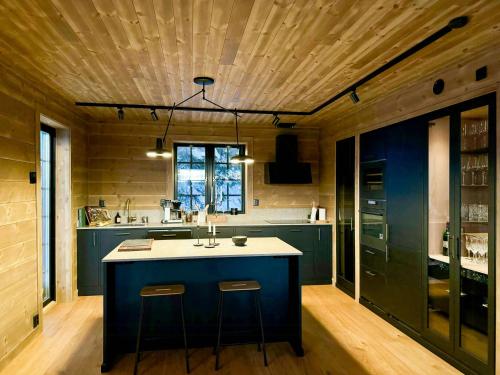 a kitchen with a blue island with two bar stools at Mountain Cabin With Views Over Jämtland's Expanse in Storhågna