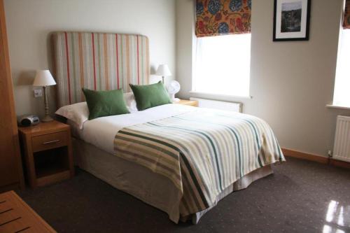 a bedroom with a large bed with green pillows at The Mitre Inn in Knaresborough