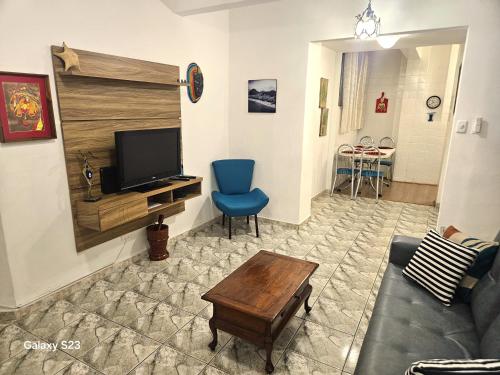 a living room with a tv and a blue chair at Edificio ALONE com terraço na quadra da praia, espaçoso e silencioso in Rio de Janeiro