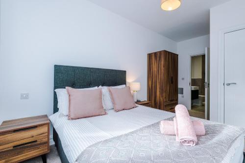een slaapkamer met een groot bed met roze kussens bij Modern Leeds Central Stay -2 min walk from station in Leeds