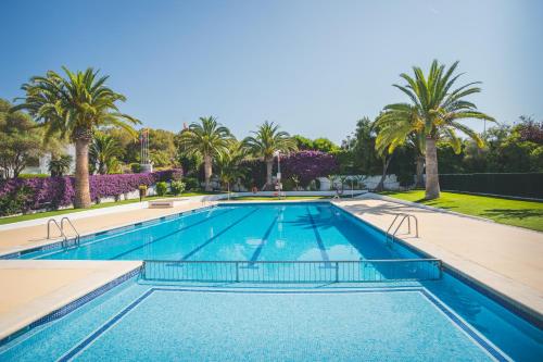 a swimming pool with palm trees in the background at HolaCamp Sitges Relax in Sitges