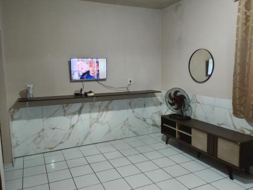 a bathroom with a tv on a counter and a mirror at Casa com 1 cama de casal e 1 cama de solteiro in Serra