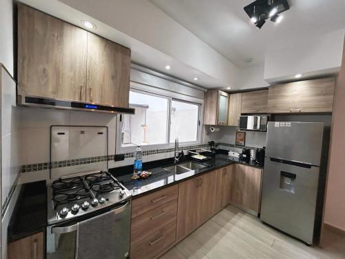 eine Küche mit Holzschränken und Geräten aus Edelstahl in der Unterkunft Vivi la comodidad de una casa pensada para vos in Diamante