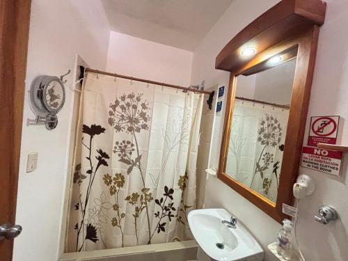 ein Bad mit einem Duschvorhang mit Blumen darauf in der Unterkunft The Galapagos Pearl B&B in Puerto Ayora