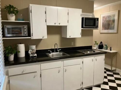 a kitchen with white cabinets and a sink and microwave at Bright 1BR Hideaway Close to UL Lafayette in Lafayette