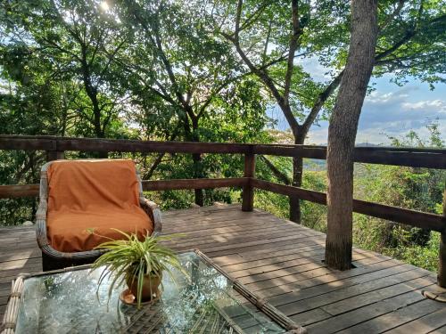 a chair and a glass table on a wooden deck at Chalé Rústico 3 - Retiro Andaluz in Brumadinho
