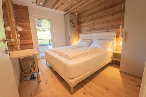 a bedroom with a white bed with a wooden wall at Nestzeit in Eben im Pongau