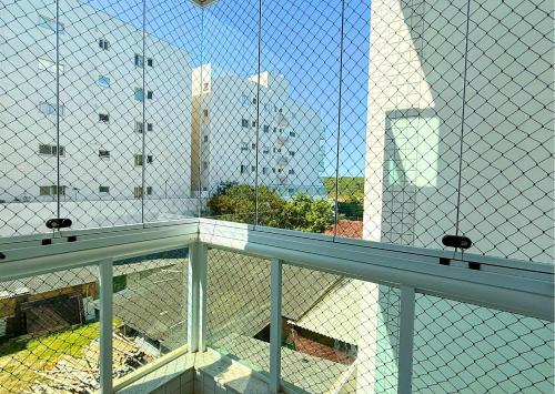 a view of a building through a chain link fence at RefugioBacutia- Prédio FRENTE MAR Bacutia- 6 pessoas- 3 Quartos com AR sendo 1 suite - varanda- sala de estar e jantar Ampla -Piscina e Sauna no Prédio in Guarapari