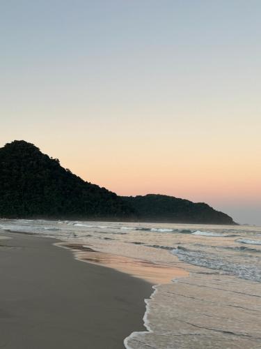 an empty beach with a mountain in the background at Drop House Hostel in Ubatuba