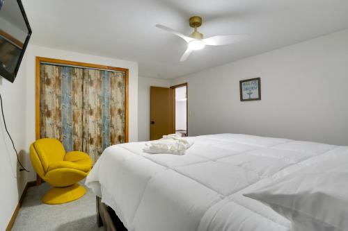 a bedroom with a white bed and a yellow chair at 6 Mi to Barr Lake Apt with Hot Tub Access! in Brighton