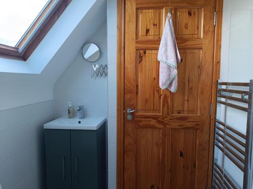 a bathroom with a wooden door and a sink at Cottage on the grounds of Rathmullan House Hotel in Rathmullan